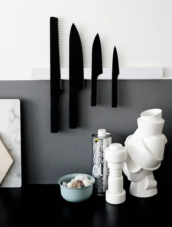 Moodboard reference: black knives mounted on a grey wall above white ceramics