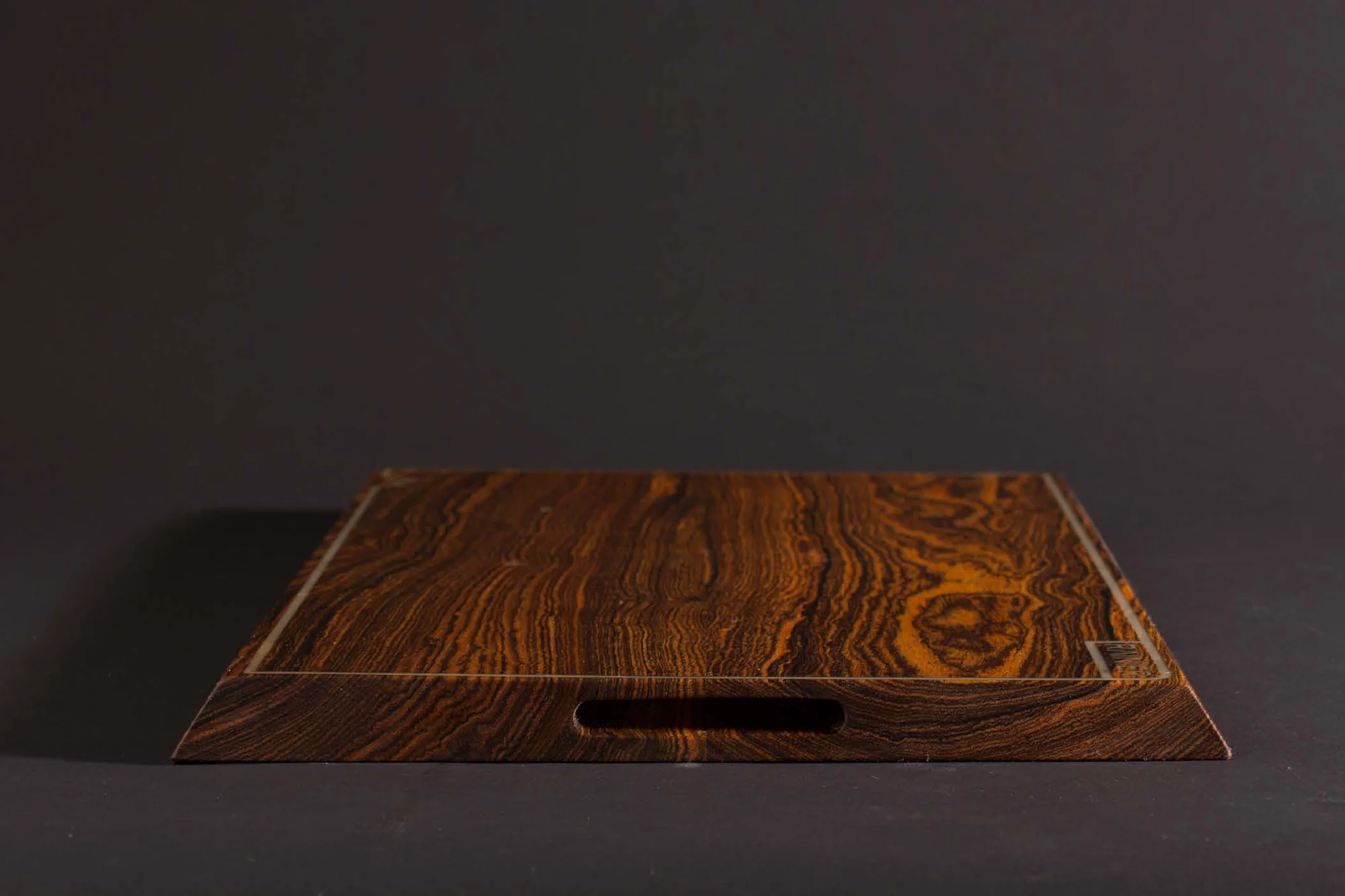The finished board seen straight on, its inlaid border line and recessed handle catching the light