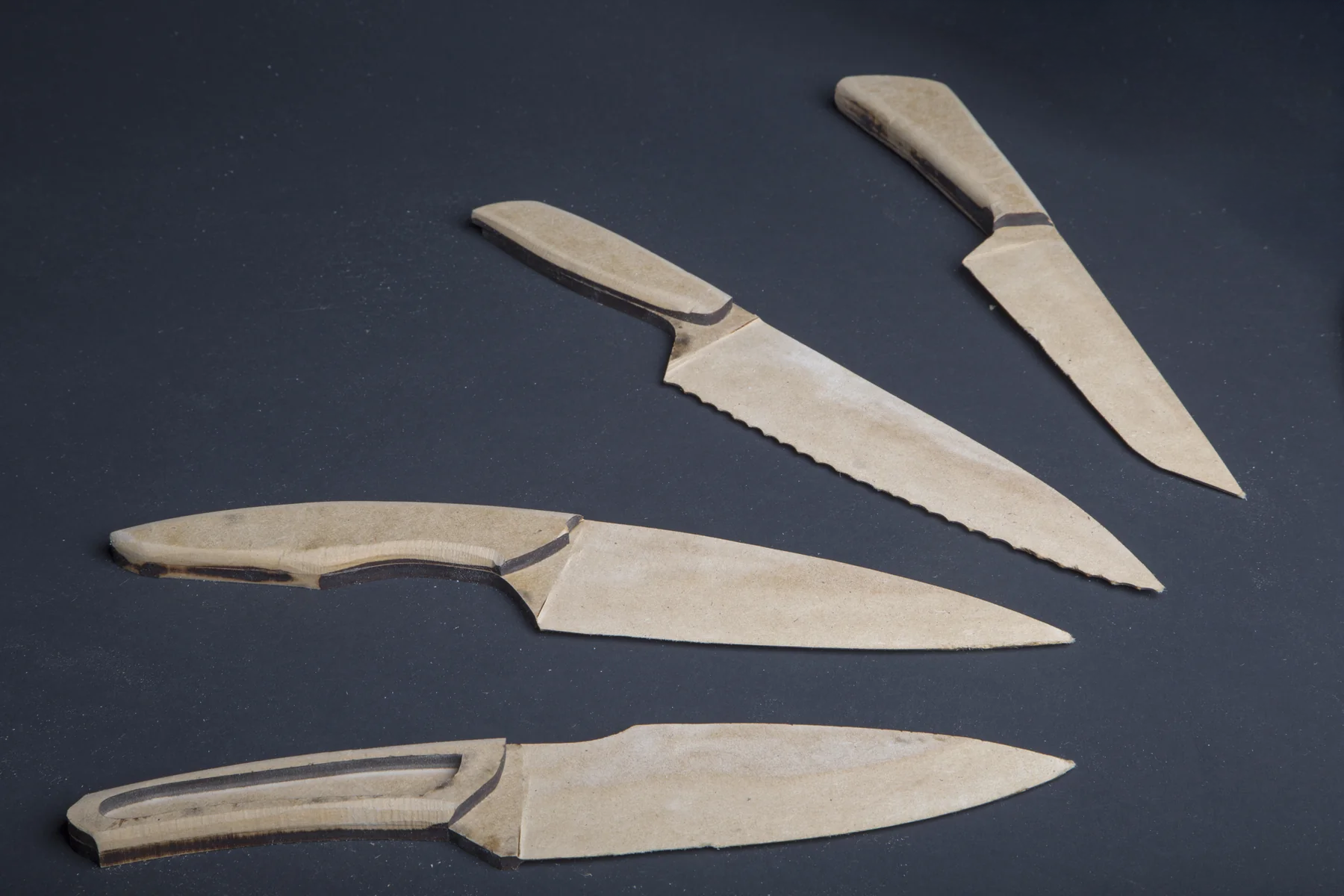 Four wooden knife prototypes fanned out on grey